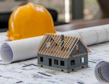 Maquette de maison avec casque de chantier et plans, représentant un projet de crédit travaux.